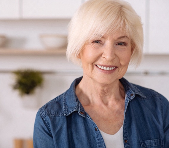 Senior woman in denim jacket smiling with dentures in Fort Worth