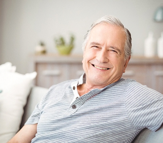 Senior man with dentures relaxing on his couch