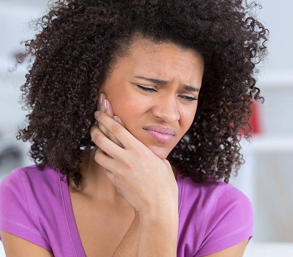 Woman in need of emergency dentistry holding jaw in pain