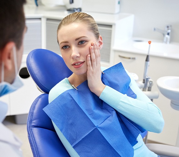 Woman holding jaw in need of emergency dentistry