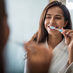 Woman brushing teeth in Fort Worth