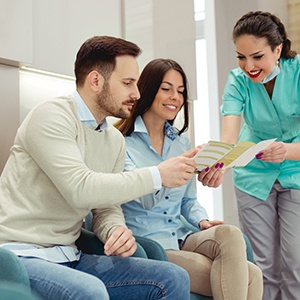 dental team member showing a pamphlet to two patients 