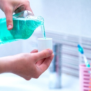 Pouring mouthwash as part of post-op care following dental implant surgery