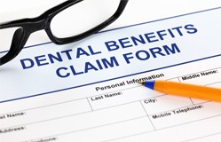 Pen and glasses lying on dental benefits claim form