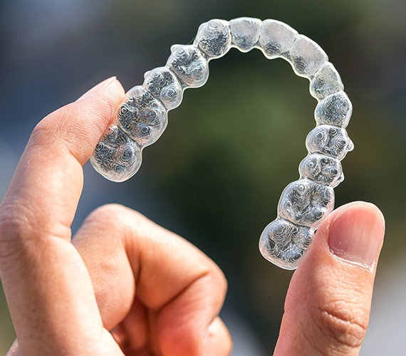 Hand holding an Invisalign tray