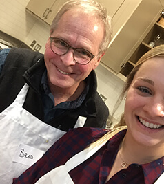 Doctor McConnell and his daughter cooking wearing matching aprons