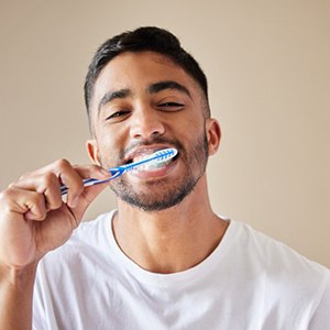 a man brushing his teeth and smiling