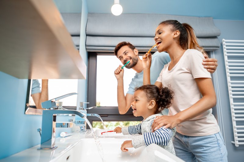 family brushing teeth in bathroom together