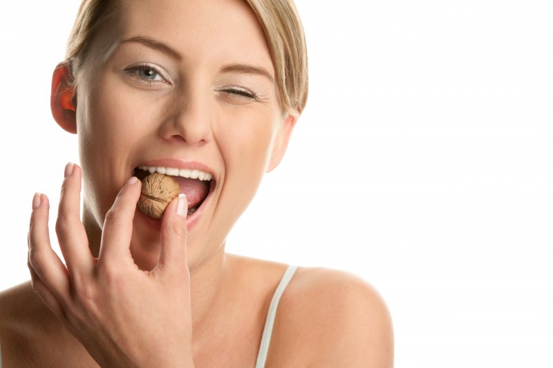 Woman biting walnut.