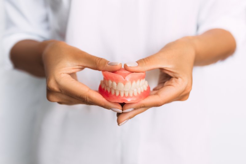 A dentist holding dentures in his hands