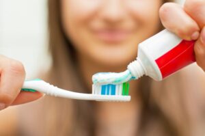 Woman putting fluoride toothpaste on her toothbrush