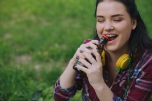 Woman opening a bottle with her teeth