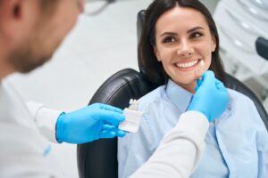 Dentist trying out veneers with smiling patient in dentist’s chair.