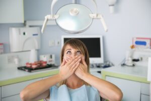 Patient in fear holding her hands over mouth.